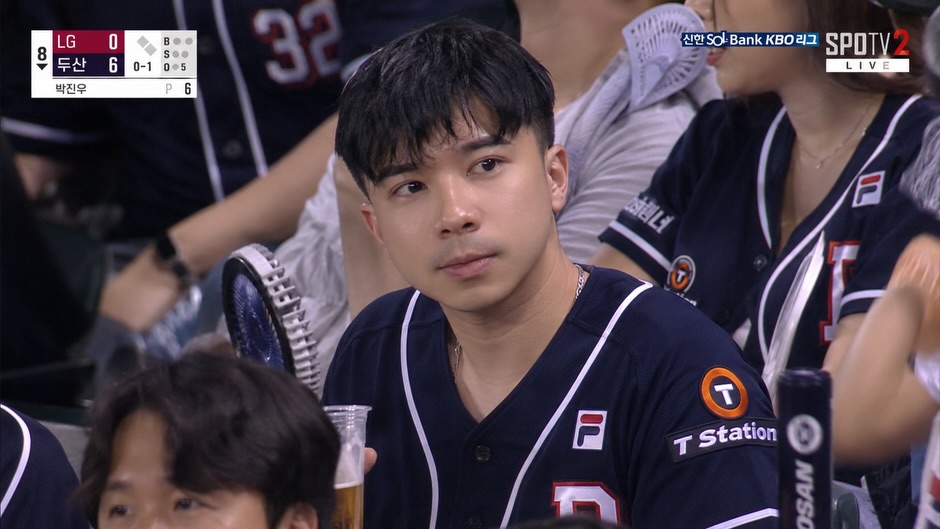 Sports broadcast screenshot of a fan in the stadium crowd